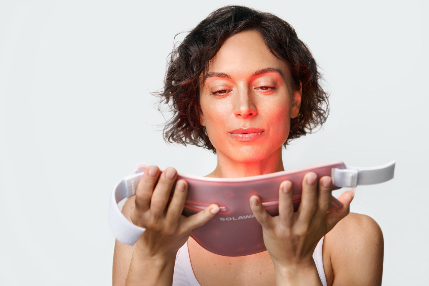 An image of a woman looking at red light therapy mask
