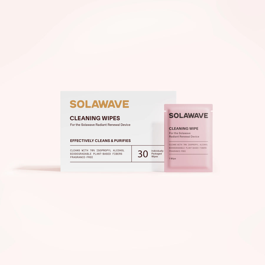 A white Solawave Light Therapy Device Cleaning Wipes box sits by a pink packet. The box features 30 biodegradable, alcohol-free, plant-based, and fragrance-free wipes for gentle, eco-friendly cleaning.