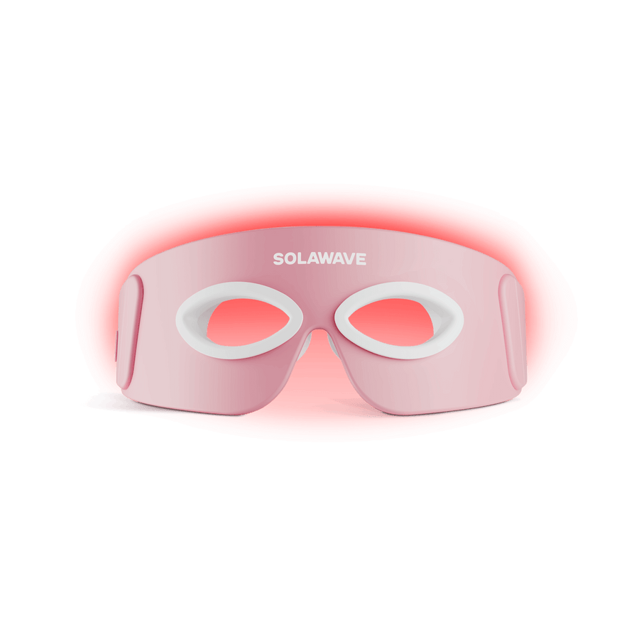 The SolaWave Radiant Renewal Eye Recovery Pro, a pink LED mask with oval eye cutouts, offers soothing red light therapy for dark circles. Its an effective eye recovery device and is shown front-facing against a plain background.
