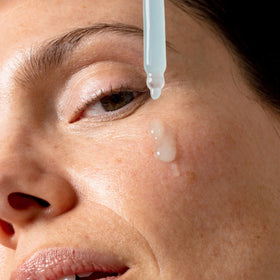 An image of a woman applying face serum to her face || 100mL