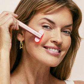 An image of a woman using a red light wand for her face || Rose Gold