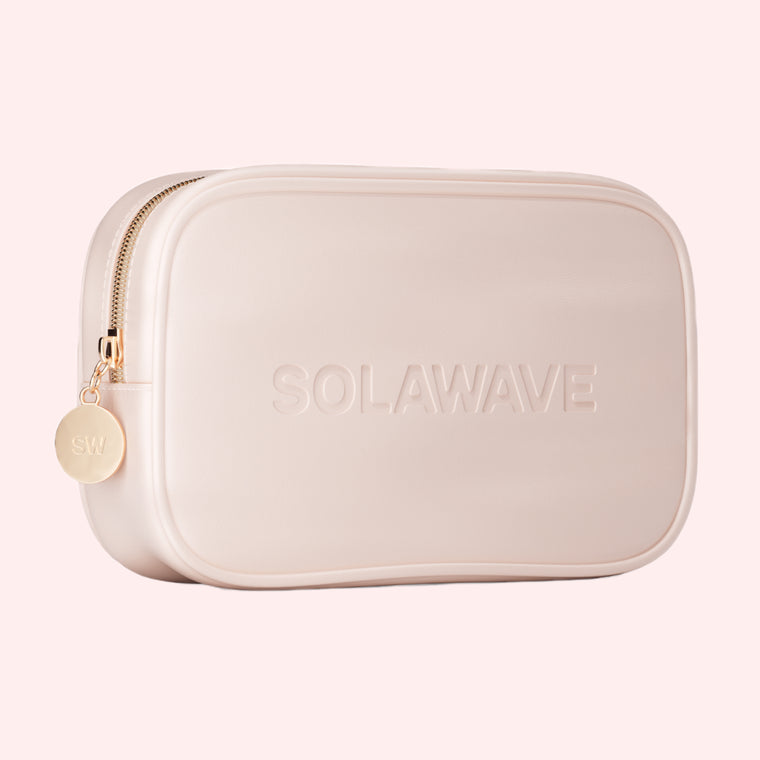Solawaves Luxury Vegan Leather Travel Bag in mauve features a gold zipper with a circular SW pull and SOLAWAVE embossed on the front. Its the perfect stylish companion for on-the-go essentials, shown against a soft peach background.