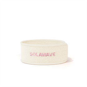 The Get Ready Headband by Solawave is a white fleece accessory with Solawave embroidered in pink on the front. It boasts an adjustable velcro design, perfectly suiting your skincare routine with its clean and minimalist style.