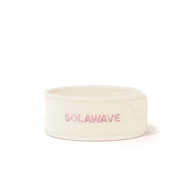 The Get Ready Headband by Solawave is a white fleece accessory with Solawave embroidered in pink on the front. It boasts an adjustable velcro design, perfectly suiting your skincare routine with its clean and minimalist style.