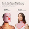 Two women are wearing Solawave skincare masks; one dons a full face mask and the other a neck and chest mask. They highlight the LightBoost Face & Neck Serum, enriched with growth factors, to boost light therapy effects for optimal skin renewal.