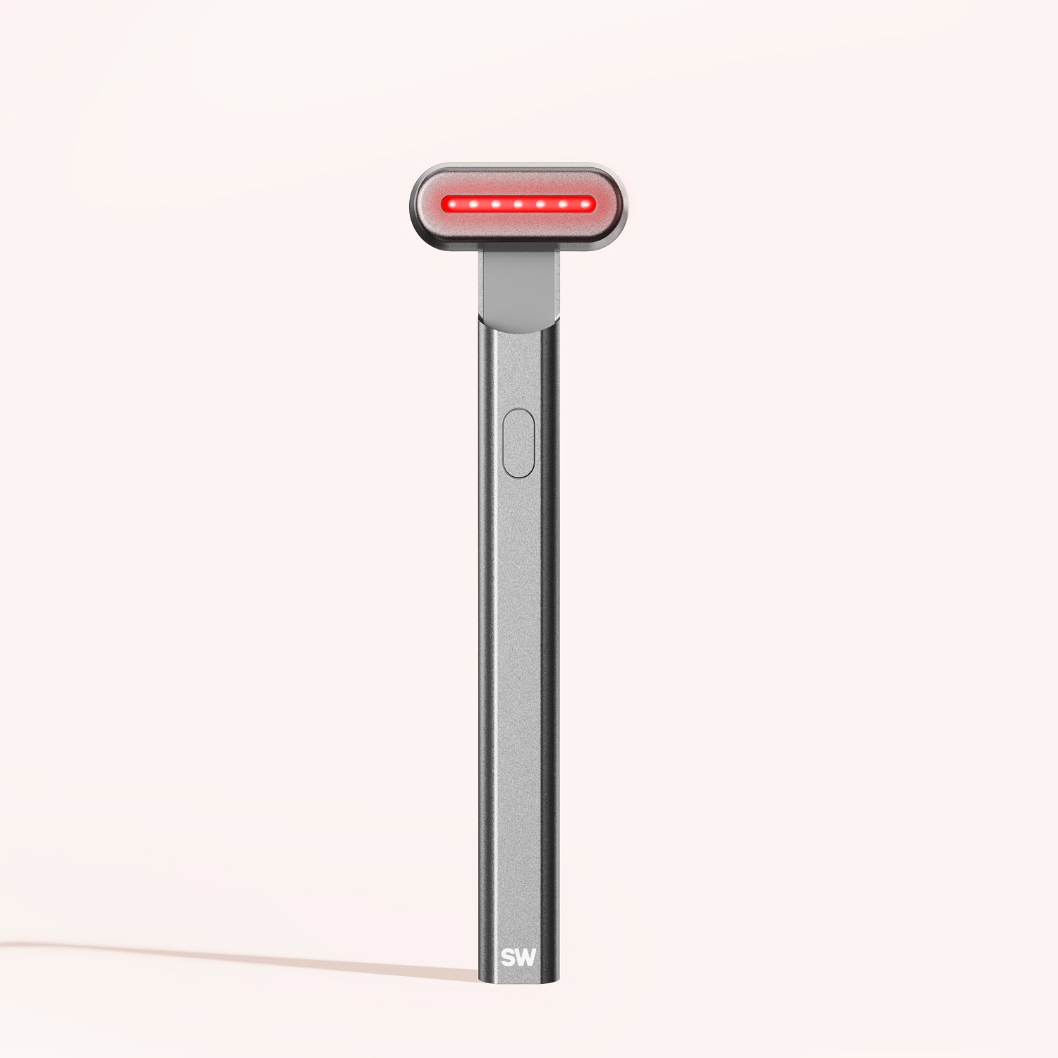 A sleek, metallic 4-in-1 Radiant Renewal Skincare Wand by SolaWave stands upright against a neutral backdrop. Featuring an elongated handle and red LED strip, this advanced device is designed to effectively reduce fine lines through Red Light Therapy. || Charcoal
