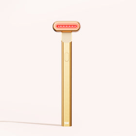 The 4-in-1 Radiant Renewal Skincare Wand by SolaWave, featuring a gold finish and a T-shaped design with red LED lights at the head, stands upright against a light background, highlighting its advanced skincare technology to reduce fine lines. || Gold 