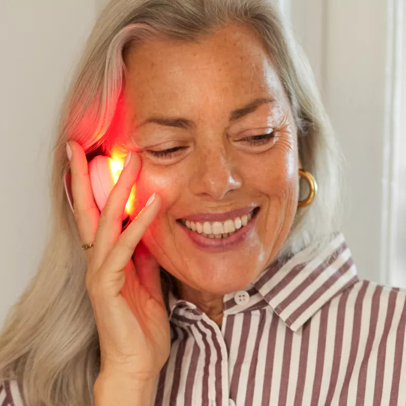Woman using the Solawave Radiant Renewal 2-in-1 Skincare Mini with red light therapy on her face