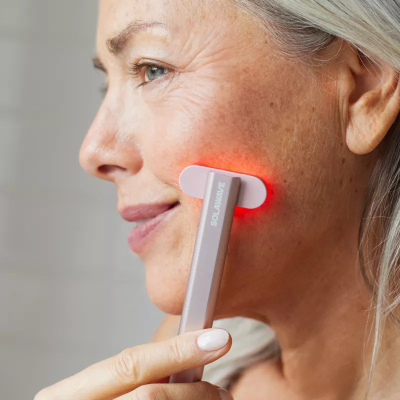 Woman using the Solawave 4-in-1 Radiant Renewal Skincare Wand with red light therapy on her cheek
