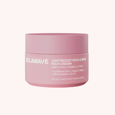 Pink cylindrical jar of Solawave Lightboost Face & Neck Rich Cream with white text on label.